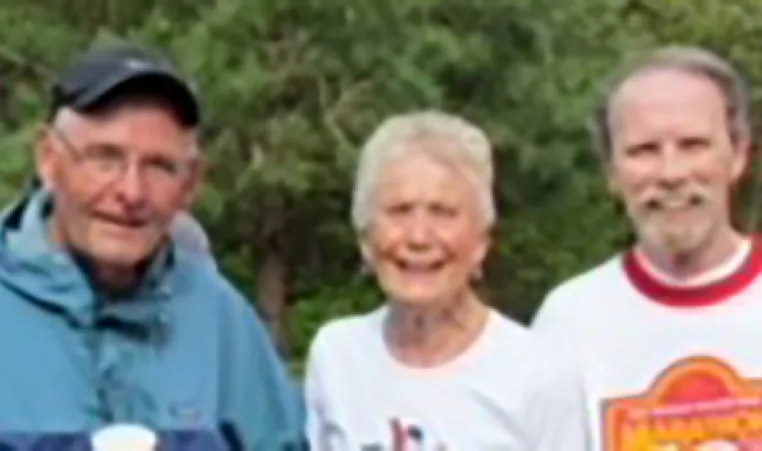 two older men and an older woman smiling at the camera after running a 10k race